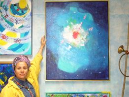 Eine Person zeigt auf ein abstraktes, blaues Gemälde an der Wand.