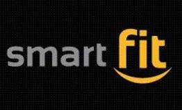 Logotipo da academia Smart Fit em fundo preto, com "smart" em cinza e "fit" em amarelo com sorriso.