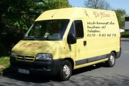 Gelber Eiswagen mit der Aufschrift "Eis Milano" und Telefonnummer an der Seite geparkt auf der Straße.