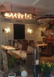 Gemütliches Restaurant mit Holzmöbeln, Pflanzen und Kerzenlicht, leere Tische und Stühle.