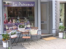 Kleines Geschäft namens "La Provence" mit Tisch, Stühlen und Pflanzen vor dem Eingang.