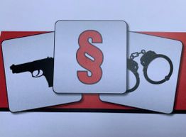 Illustration zeigt Pistole, Paragraphenzeichen und Handschellen auf rotem Hintergrund.