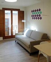 Sala de estar moderna con sofá gris, mesa de comedor y ventana con contraventanas de madera.