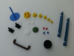 Verschiedene bunte Plastikbauteile auf weißem Hintergrund angeordnet.