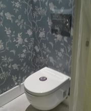 Baño con inodoro blanco y papel tapiz floral azul.