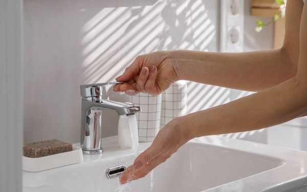 Einen Frau wäscht sich ihre Hände unter ihrem neuen Wasserhahn.