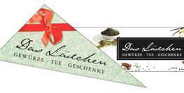 Dreieckiger Flyer mit roter Schleife, Text: "Das Lädchen, Gewürze, Tee, Geschenke".