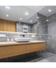 Baño moderno con lavabo de cerámica, espejo amplio y pared de azulejos grises.