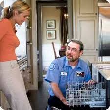 Vrouw spreekt met monteur die vaatwasser repareert in een keuken.