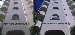 Dois prédios brancos com escrita "Persianas GN Tropical" na fachada.