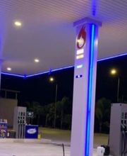 Stazione di servizio illuminata di notte con luci blu e pompe di benzina.