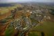 Luftaufnahme einer weitläufigen Stadtlandschaft mit Feldern und Wäldern im Herbst.