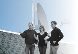 Drei Personen posieren auf einem Dach vor einer Satellitenschüssel, Daumen nach oben.