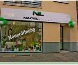 Geschäftsfassade mit "Neueröffnung" auf dem Schaufenster und grüner Dekoration.