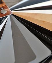 Fächer mit Farbmusterkarten in verschiedenen Tönen auf einer grauen Oberfläche.