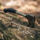 A hatchet stuck in a fallen tree trunk outdoors, with a blurred background.