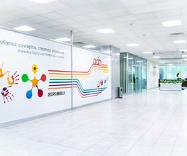 Pasillo moderno con mural colorido de huellas y líneas en una oficina de marketing digital.