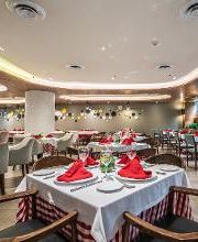 Restaurante elegante con mesas bien dispuestas, manteles blancos y servilletas rojas.