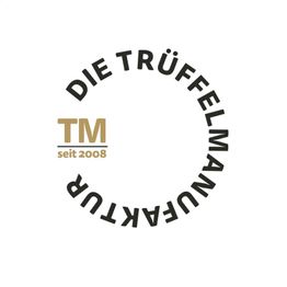 Logo: „Die Trüffelmanufaktur“ in einem Kreis, daneben „TM seit 2008“ in Gold.
