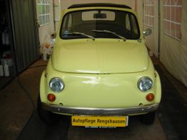 Gelber Oldtimer in einer Garage, mit dem Schild "Autopflege Rengshausen" an der Front.