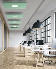 Oficina moderna con escritorios blancos, sillas y ventanas grandes. Lámparas negras cuelgan del techo.