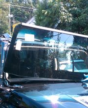 Person montiert neue Windschutzscheibe an einem schwarzen Auto.