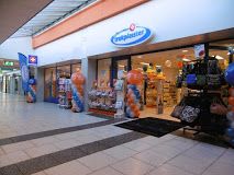 Winkelpassage met een drogisterij, versierd met oranje en blauwe ballonnen.