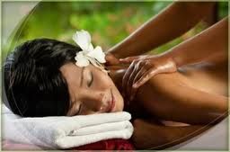 Person erhält entspannende Massage mit Blume im Haar, liegend auf Handtuch.