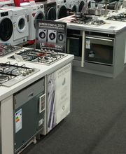 Negozio di elettrodomestici: lavatrici, forni e piani cottura esposti su lunghi banconi.