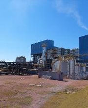 Indústria com estruturas metálicas e tanques sob céu azul claro.