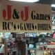 Sign for J&J Games store, featuring RC's, games, and hobbies, with shelves of items below.