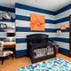 Nautical-themed nursery with blue striped walls, a black crib, and ocean-themed decor.