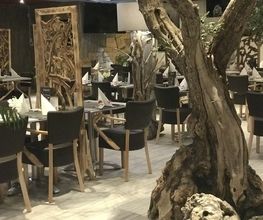 Gemütliches Restaurant mit Holzmöbeln und verwittertem Baumstamm als Dekoration.