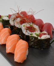 Plato de sushi variado con nigiri de salmón y atún. Decorado con cebollino y hilos de chile rojo.