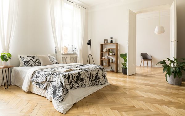 Ein Schlafzimmer mit einem Parkettboden in Fischgrätoptik. 