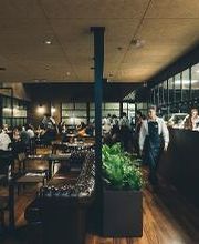 Restaurante moderno e elegante com pessoas jantando e garçons servindo em um ambiente aconchegante.