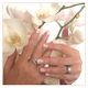 Hände mit Nageldesign und Ringen halten weiße Orchideen.