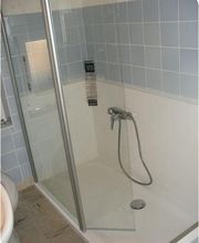 Dusche mit Glaswand, blauen Fliesen und Handbrause in einem Badezimmer.