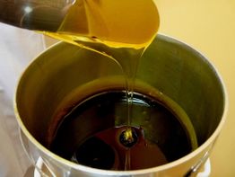 Goldgelbe Flüssigkeit fließt in einen silbernen Metallbehälter.