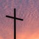 Silhouette of a cross against a vibrant pink and orange sunset sky.