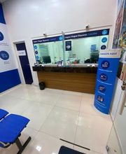 Sala de espera azul com cadeiras e balcão de atendimento em ambiente comercial.