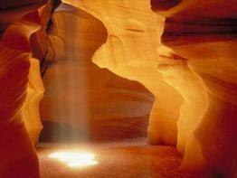 Lichtstrahl im orangefarbenen Antelope Canyon, beleuchtet Sandboden.