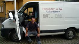 Ein Mann sitzt in der geöffneten Tür eines weißen Lieferwagens mit Werbeaufdruck.