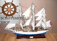 Modell eines Segelschiffs auf einem Tisch, links oben Steuerrad und Text "SCHIFFSMODELL-SHOP".