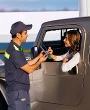Hombre atendiendo a mujer en una camioneta en una gasolinera.