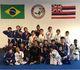 Martial arts kids class posing in gi under Brazil and Hawaii flags at jiu-jitsu academy.