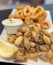 Plato de calamares y pescaditos fritos con mayonesa y limón en un plato blanco.