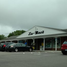 Parking lot outside Lu-Mac's store on a cloudy day, with several cars parked in front.