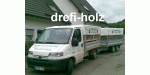 Lieferwagen mit Anhänger vor einem Haus, beschriftet mit "drefi-holz".