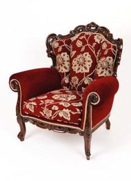 Roter Sessel mit floralen Mustern und Holzverzierungen im antiken Stil.
